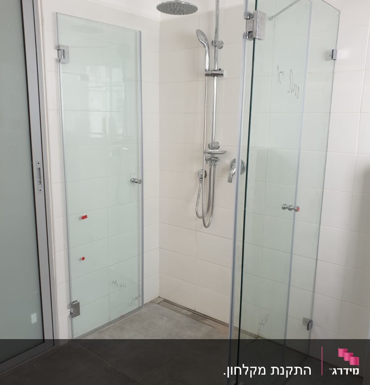 מקלחת עם דלתות זכוכית וראש מקלחת מתכתי